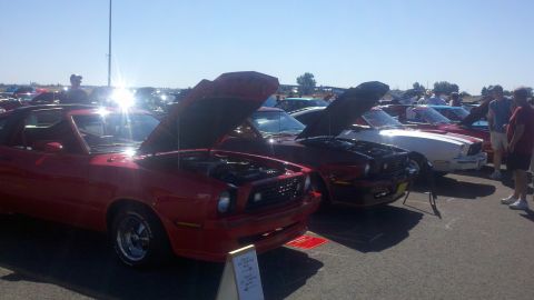 1978 Ford Mustang II - Several classic cars are displayed with their hoods up under a clear sky at an outdoor event.