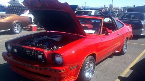 1978 Ford Mustang II - A red 1978 Ford Mustang II coupe is parked with its hood open, revealing the engine bay.