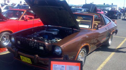1978 Ford Mustang II - Brown 1978 Ford Mustang II on display at a car show, hood and engine visible.