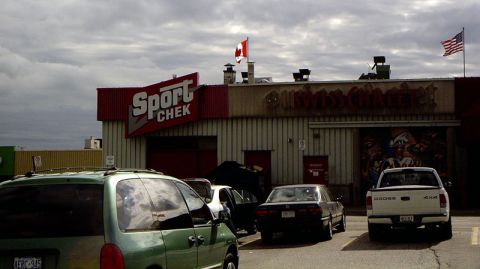 1999 Ford Crown Victoria - A cloudy day scene shows multiple vehicles parked outside a commercial building with prominent signage.