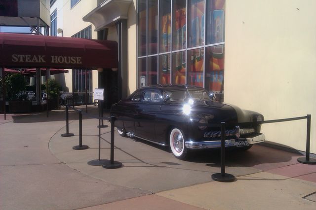 Black 1950s coupe with whitewall tires parked outside a steakhouse