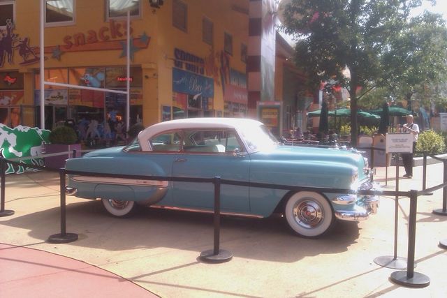 Blue and white two-door coupe with chrome trim and whitewall tires parked outdoors