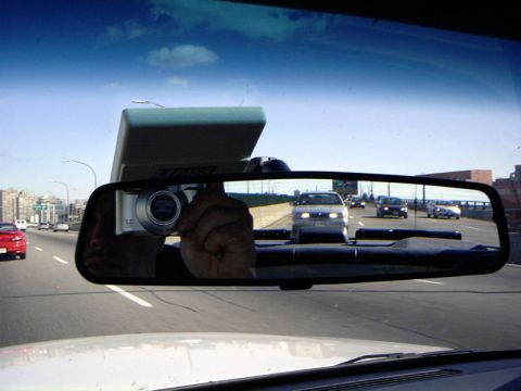 1999 Ford Crown Victoria - Traffic viewed in rearview mirror, with a camera reflected in the glass.
