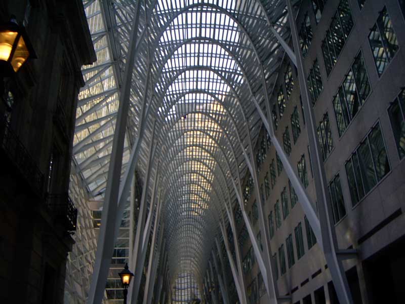 Interior of a modern building with a glass and steel arched roof and rows of windows