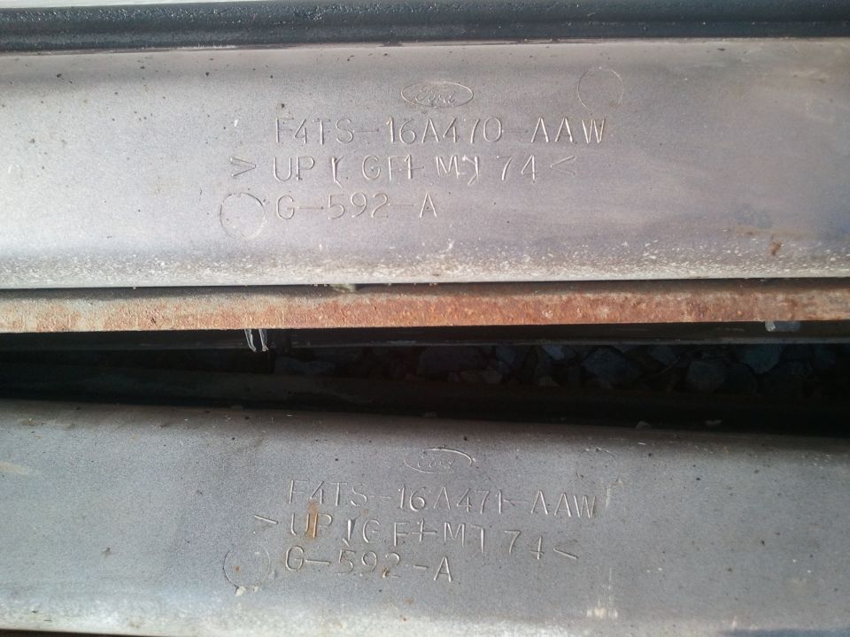Two identical metal parts stamped with Ford logo, part number F4TS-16A470-AAW, and other codes
