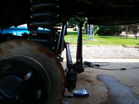 1996 Ford Bronco - Vehicle suspension parts are visible, with a power tool nearby on the concrete surface.