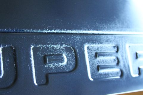 2006 Ford F-350 - The 'SUPER DUTY' emblem shows wear and tear, with visible paint chipping and damage.