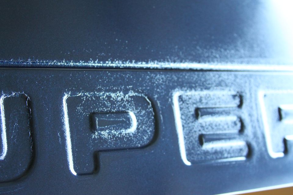 Close-up of a dark gray 'SUPER DUTY' emblem with white paint chips and scuffs