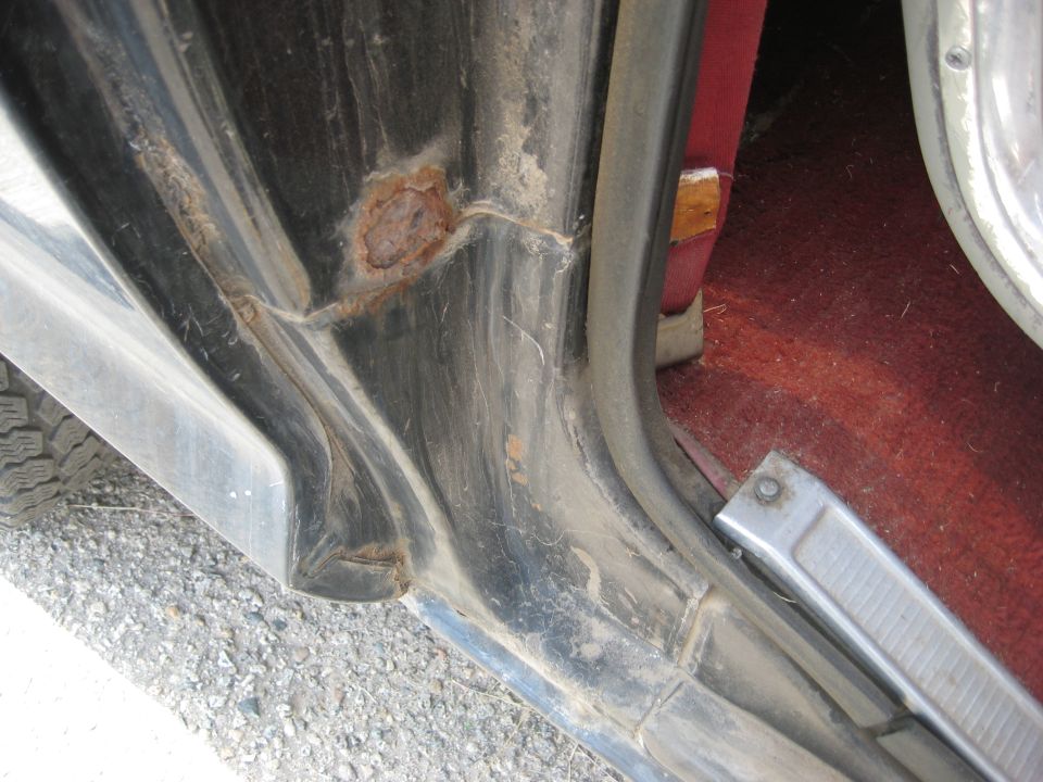 Door jamb of a vehicle showing rust damage and worn metal trim