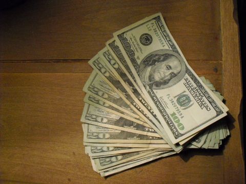 1986 Ford Bronco - A fan of US currency, including $100 and $20 bills, is displayed on a wooden surface.