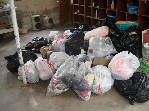 1986 Ford Bronco - A collection of trash bags and other items are piled on the floor in a room with concrete walls and wooden shelves.