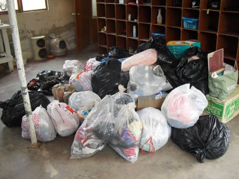 1986 Ford Bronco - A collection of trash bags and boxes are piled on the floor in a room with shelving units and a cat litter box.