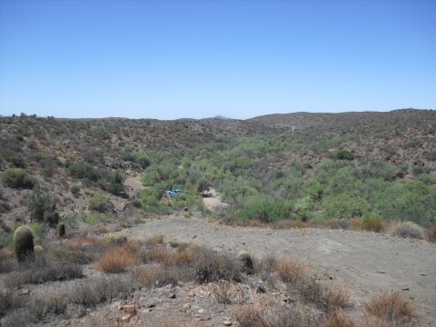 1986 Ford Bronco - A lone blue pickup truck is visible in a remote, arid landscape under a clear blue sky.