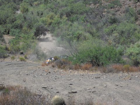 1986 Ford Bronco - An off-road vehicle navigates a dusty trail through arid terrain.