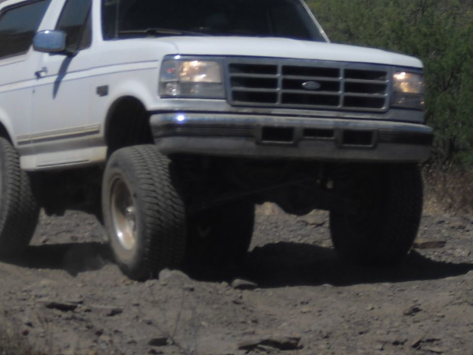 White SUV with prominent grille and headlights driving off-road
