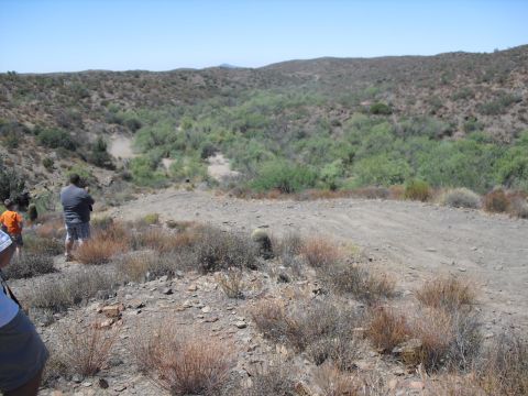 1986 Ford Bronco - Off-road enthusiasts observe the terrain in a desert-like landscape.