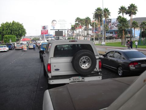 1986 Ford Bronco - A white Ford Bronco is seen in traffic, with a spare tire mounted on its rear.