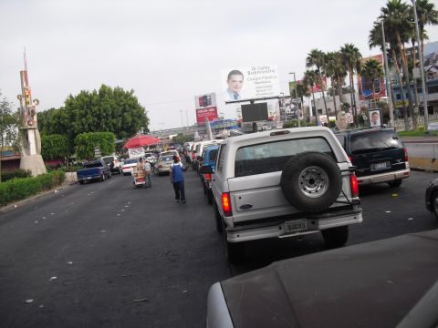 1986 Ford Bronco - Silver Ford Bronco with spare tire on back is seen in traffic on a cloudy day.