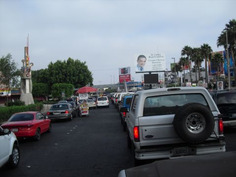 1986 Ford Bronco - A silver SUV is stuck in traffic, with a billboard advertising plastic surgery in the background.