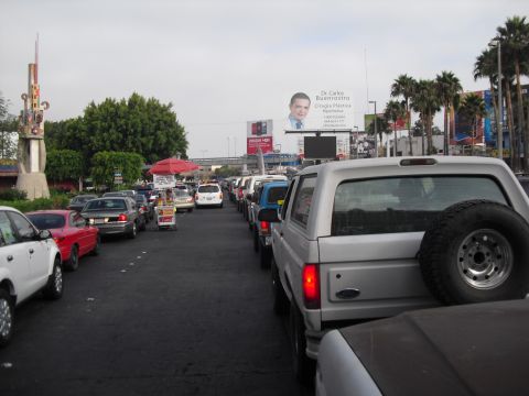 1986 Ford Bronco - A silver Ford Bronco is seen from the rear in a line of traffic, with a spare tire mounted externally.