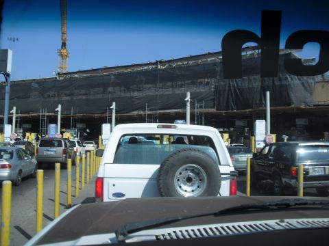 1986 Ford Bronco - A white 1986 Ford Bronco is seen from behind while waiting in traffic at a border crossing or toll booth.