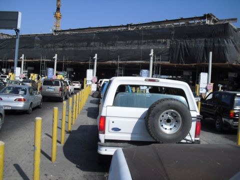 1986 Ford Bronco - White SUV with spare tire on rear bumper, waiting in line at a border crossing.