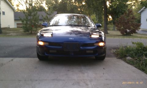 1994 Ford Probe - Front view of a blue Ford Probe with its pop-up headlights illuminated.