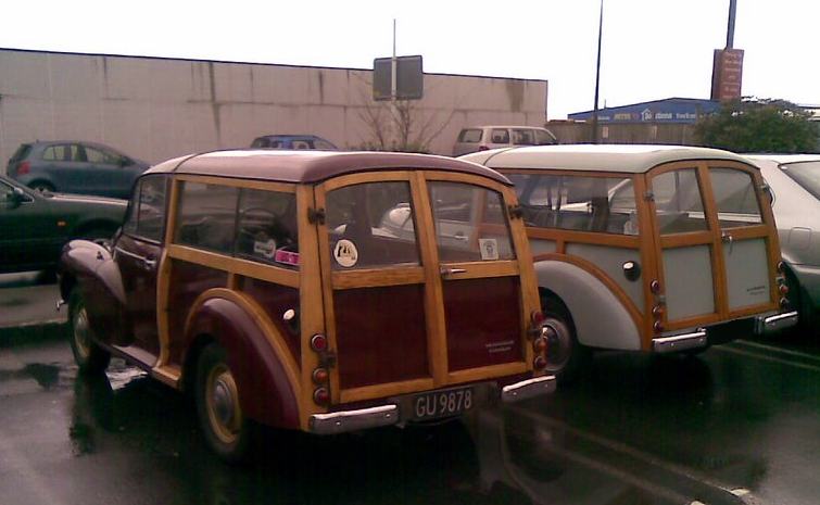 Two wood-paneled station wagons parked side-by-side, one maroon and one light gray