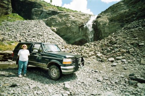 1995 Ford Bronco - A woman poses with her Ford Bronco in a , mountainous landscape a cascading waterfall.