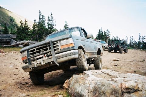 1995 Ford Bronco - 1995 Ford Bronco navigating rocky terrain on an off-road trail.