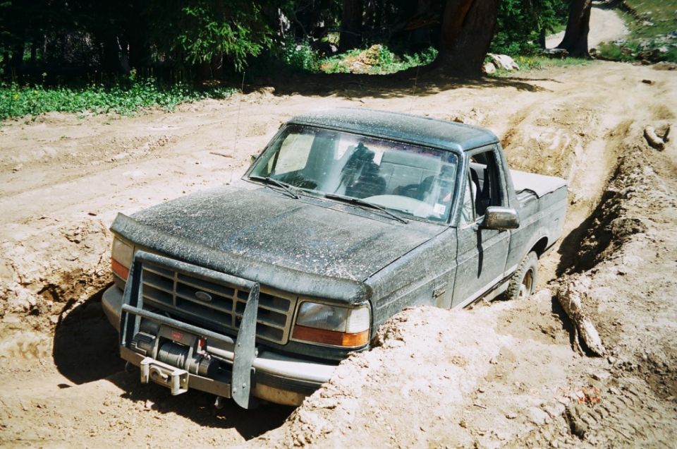 Ford F-Series truck stuck in a dirt trench, winch on front bumper