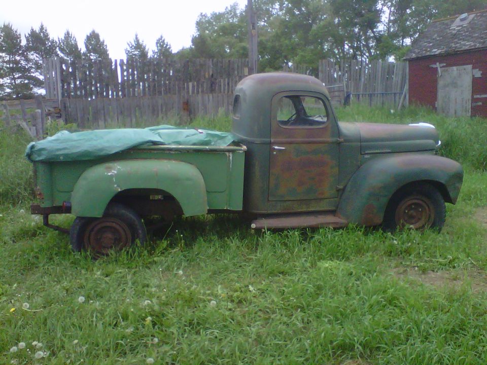Green pickup truck side view, tarp on bed
