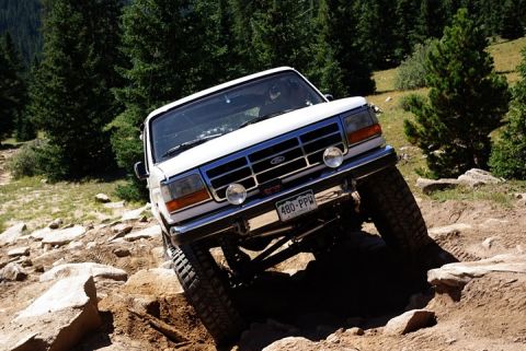 1995 Ford Bronco - This Ford Bronco is tackling a challenging off-road path with steep inclines and large rocks.