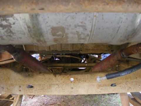 1978 Ford Bronco - Underside view reveals a fuel tank and exhaust system components on a heavily rusted vehicle frame.