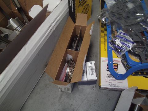 1991 Chevrolet Blazer - Various engine parts, including a gasket set, are organized in cardboard boxes on a concrete floor.