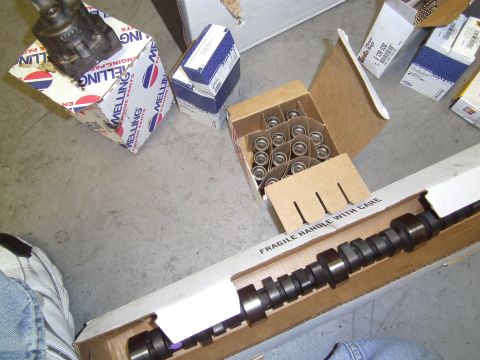 1991 Chevrolet Blazer - Engine parts laid out on a concrete floor, including a camshaft and a box of lifters.