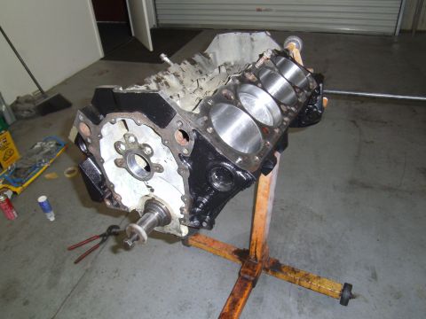 1991 Chevrolet Blazer - Engine block on a stand with visible cylinders and crankshaft flange, with tools on the floor.