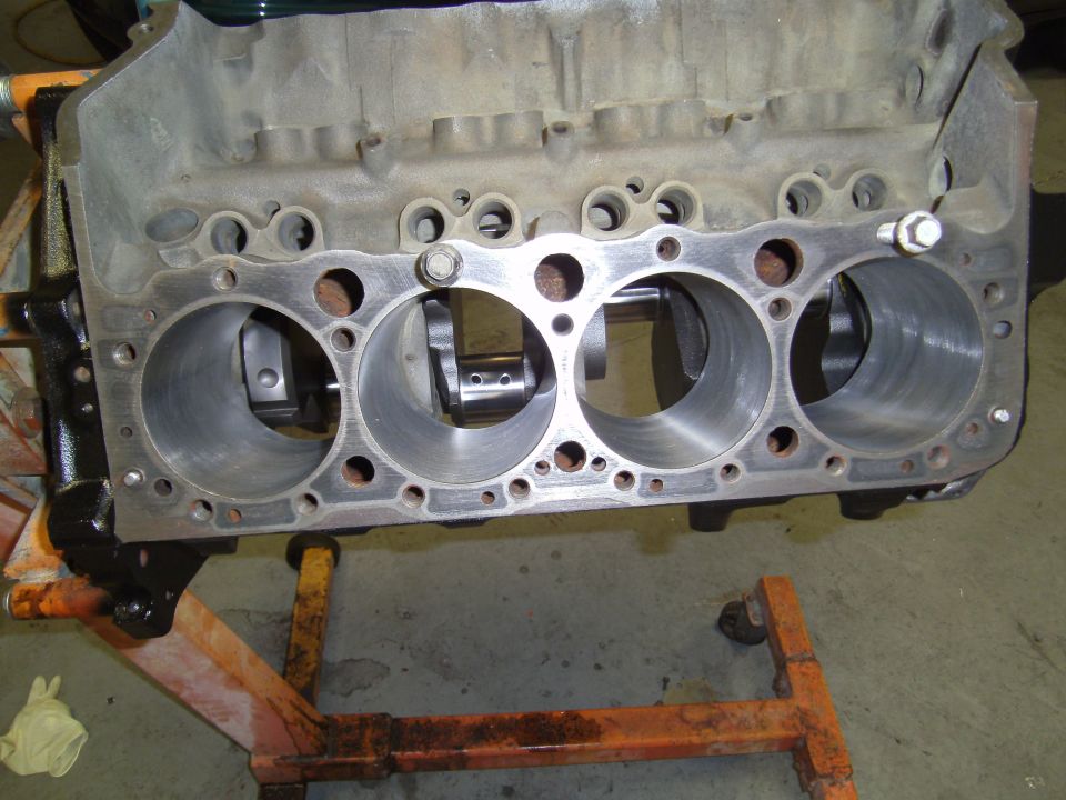 Engine block with crankshaft and cylinder bores visible, mounted on an engine stand