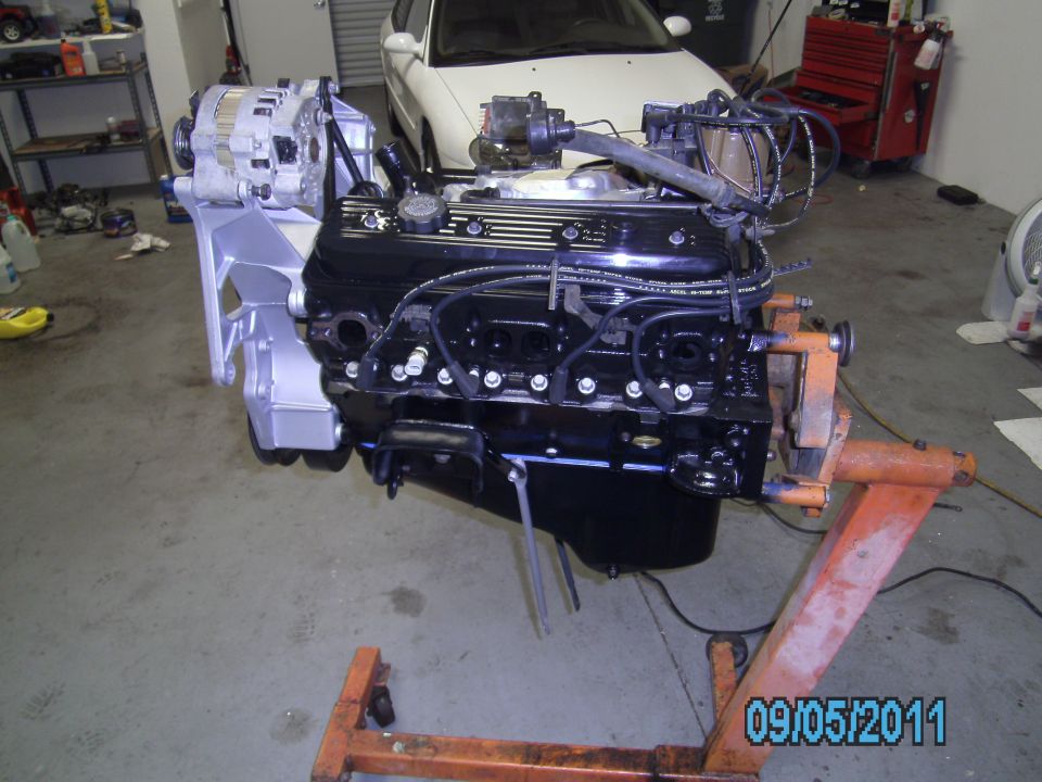 Engine on an orange stand, with alternator attached