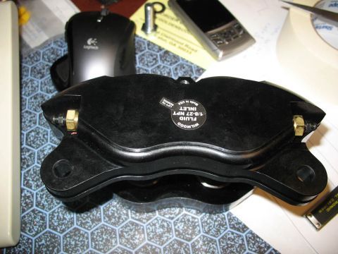 1993 Mazda MX-3 - A black Wilwood brake caliper is shown, a label indicating fluid inlet specifications.