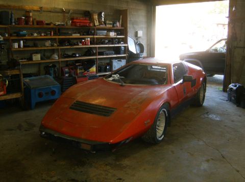 2000 Ford E350 - An orange sports car sits in a garage next to another vehicle, with shelves of tools in the background.