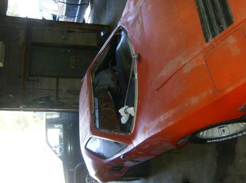 2000 Ford E350 - An orange sports car sits in a garage, showing its interior and open door. Another vehicle is visible in the background.