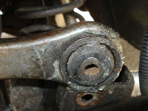 2000 Ford Crown Victoria - Worn suspension bushing on a metal control arm, showing signs of age and wear.