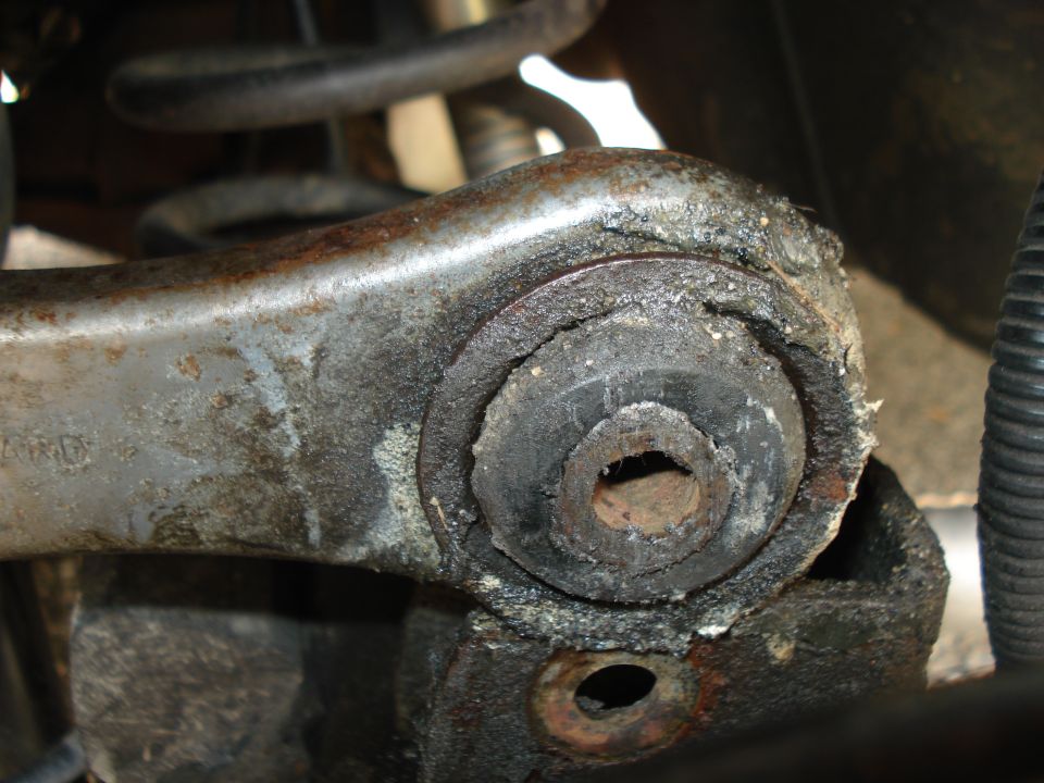 Close-up of a worn rubber suspension bushing on a metal control arm