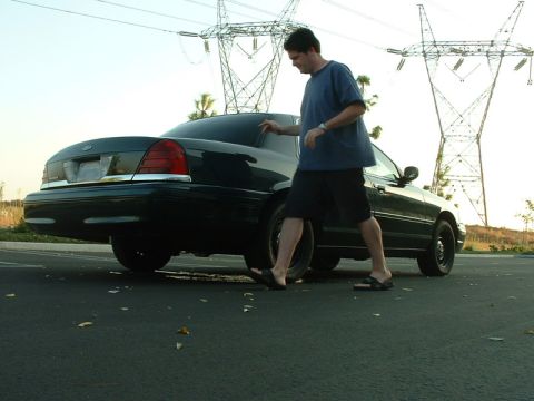 1998 Ford Crown Victoria - Man walks next to a 1998 Ford Crown Victoria parked near power lines.
