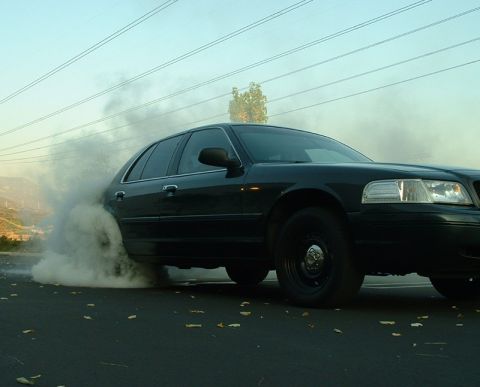 1998 Ford Crown Victoria - A black 1998 Ford Crown Victoria is performing a burnout, creating a large cloud of smoke.