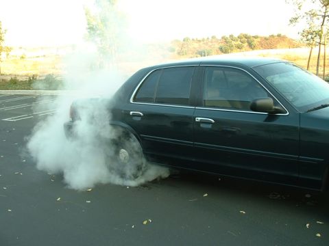 1998 Ford Crown Victoria - A dark green 1998 Ford Crown Victoria performs a burnout, with smoke billowing from the rear wheel.