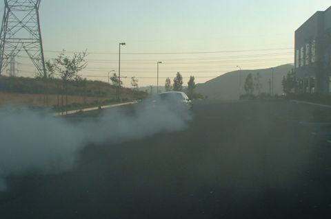 1998 Ford Crown Victoria - A car performs a burnout in an empty lot, creating a large cloud of smoke.