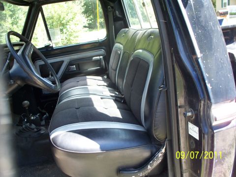 1979 Ford F-250 - The interior of a truck cab features a bench seat with striped upholstery and a view of the dashboard and steering wheel.