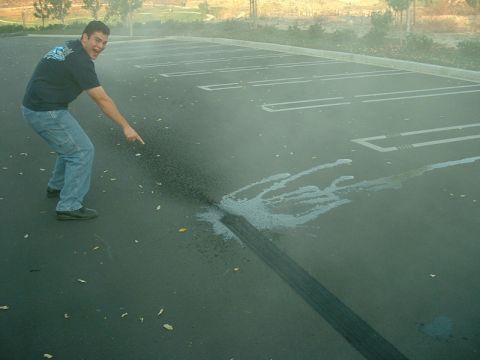 1998 Ford Crown Victoria - A man gestures towards a large tire mark and liquid spill on a parking lot surface.